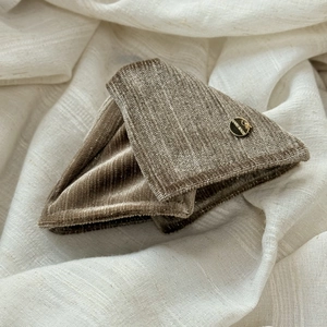 Macro detail of brown velvet hair clip with a round golden handmade metal label