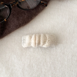 Gros plan sur une pince à cheveux en tricot crème avec texture ondulée pour l'automne