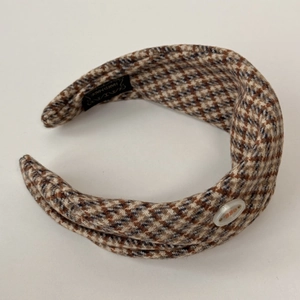 Gros plan d'un serre-tête en tweed avec bouton décoratif et étiquette tissée main
