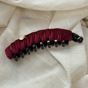 Macro shot of wine red velvet banana hair clip with handmade gold tag on linen