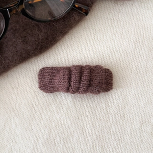Détail d'une pince à cheveux en tricot marron foncé avec texture douce en mohair