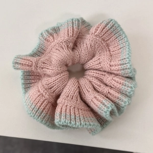Détail de la texture tricotée du chouchou rose et vert menthe aux bords ondulés