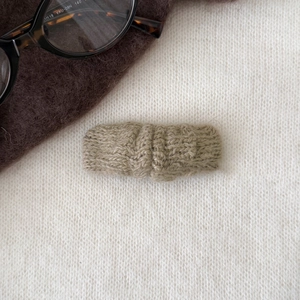 Gros plan sur une pince à cheveux en tricot vert haricot avec texture torsadée