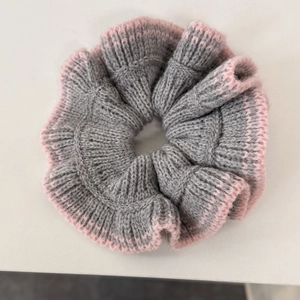 Gros plan détaillé d'un chouchou en maille grise avec bordure rose sur fond blanc