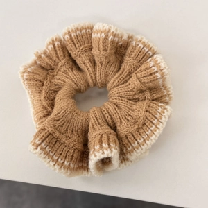 Détail d'un chouchou en maille épaisse avec texture marron beige et bords en dentelle