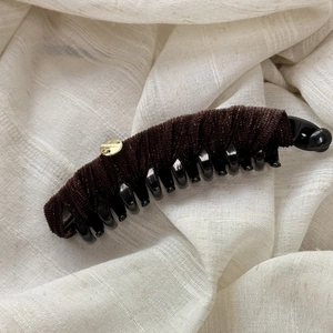 Detailed macro view of dark brown velvet banana clip with handmade gold metal tag