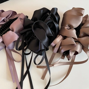 Detailansicht der plissierten Satin-Bananenspangen in Lila, Schwarz und Kaffeebraun