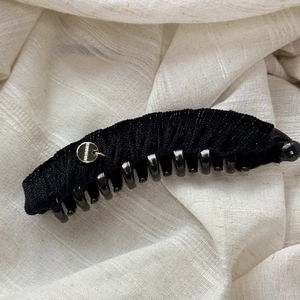 Detail of black velvet banana clip with handmade gold emblem and shimmering silver threads