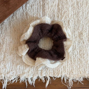 Détail d'un gros chouchou en maille bicolore avec bordure en dentelle sur fond chaleureux