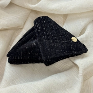 Close-up of velvet fabric with silver metallic threads and a gold handmade label