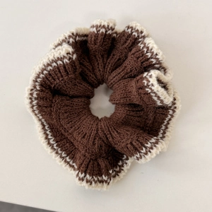 Détail d'un chouchou en tricot marron avec bordure en dentelle crème et texture douce
