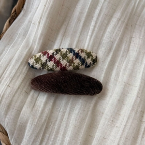 Detail of vintage tweed checkered and brown velvet clips on white linen fabric