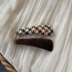 Close-up of vintage brown knit plaid and plush faux fur hair clips on white fabric