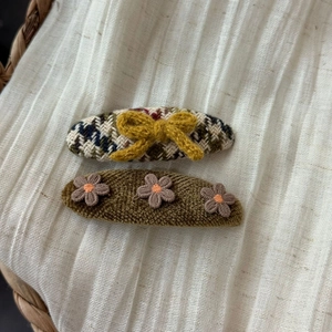 Close-up of vintage plaid cat bow and chenille flower hair clips on white fabric