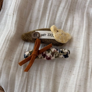 Detailed close-up of retro cat-themed hair clips with knit and tweed textures