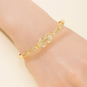 Bracelet nœud fer à cheval doré tendance avec zircons brillants sur un poignet