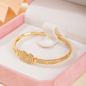Bracelet jonc doré avec nœud en fer à cheval et zircons dans un écrin à bijoux