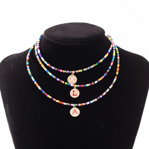 Collier à trois rangs de perles colorées avec pendentifs lettres dorées X L A sur buste