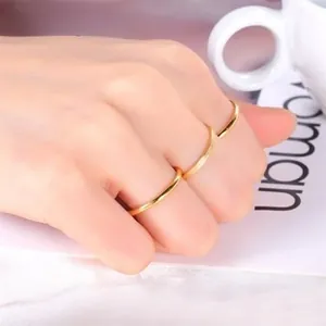 Detailed view of three minimalist gold rings worn on a hand holding a white coffee cup
