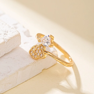 Vue macro d'une bague ouverte dorée avec un grand zircon et des petits cœurs pavés de pierres
