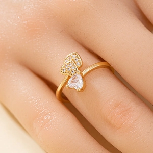 Détail d'une bague épis de blé dorée avec zircons en cœur portée au doigt