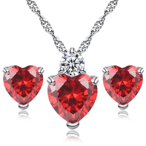 Close-up of heart-shaped garnet red zircon necklace and stud earrings set with silver finish