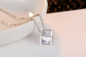Detail shot of a silver cube necklace with a brilliant round-cut zircon stone inside