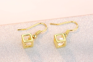 Detailed macro view of gold geometric cube earrings with sparkling round zircon inserts