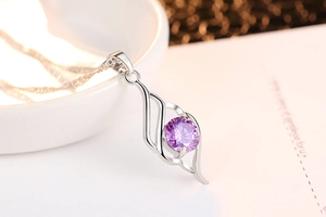 Detail of angel wing necklace featuring a purple zircon stone on silver pendant