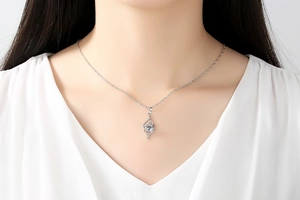 Detailed close-up of a silver angel wing pendant with a sparkling zircon on a female neck