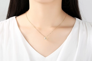 Close-up of minimalist gold square cube pendant necklace with zircon on a model