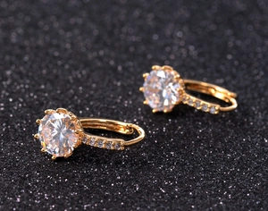Dettaglio di orecchini a cerchio dorati con zircone rotondo e micro-pavé di diamanti