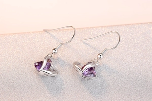 Macro shot of silver heart earrings with purple amethyst stones and micro-pave crystals