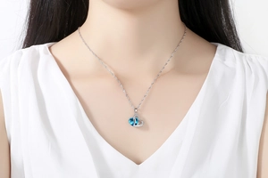 Elegant heart-shaped blue crystal pendant necklace worn by a model on a silver chain