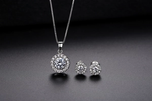 Macro detail of silver halo jewelry set featuring round cut zircon necklace and stud earrings