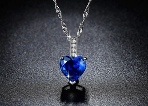 Makroansicht blauer herzförmiger Edelsteinanhänger mit vierteiligem Diamantbügel und Silberkette