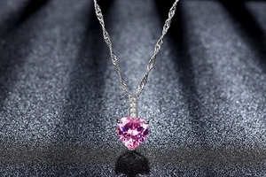 Details des rosa Herz-Zirkonia-Anhängers mit silberner Kette auf schwarzem Hintergrund