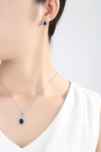 Detail shot of a model wearing a luxury silver necklace and earrings set with blue gemstones