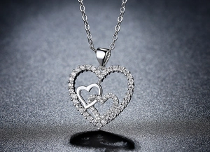 Macro close-up of interlaced heart pendants with sparkling zircons on a silver chain