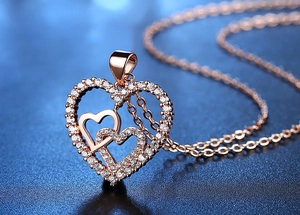 Detailed macro shot of rose gold interlocking heart pendant necklace with zircon inlay