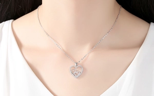 Close-up of a double heart necklace with sparkling zircons worn by a model in silver finish