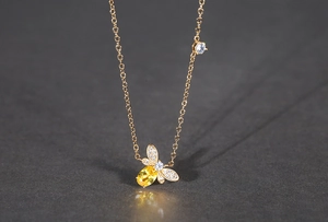 Macro d'un collier pendentif abeille doré avec pierre jaune et détails en zircon blanc