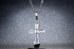 Gros plan d'un pendentif croix en argent serti de zircons baguettes sur chaîne fine