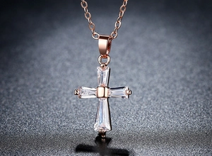 Détail du collier croix en or rose avec pierres baguette et ombre dramatique