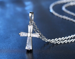 Détail macro du pendentif croix en argent serti de quatre zircons rectangulaires sur chaîne