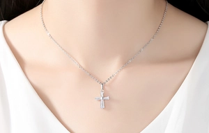 Gros plan d'un collier croix en argent avec zircons taille baguette porté par un mannequin