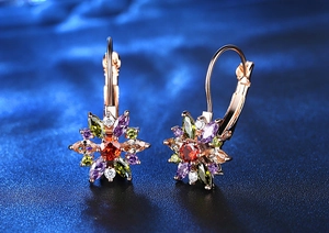 Détail macro de boucles d'oreilles fleur en zircon coloré et placage or rose