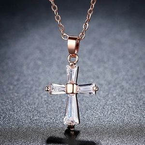 Collier avec pendentif croix en or rose et pierres de zircon sur un fond sombre