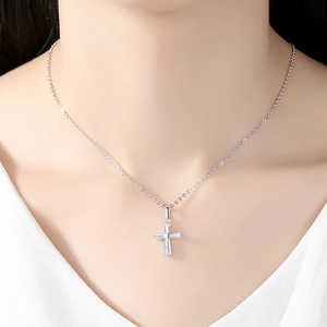 Collier croix argenté élégant avec zircons baguettes porté par un mannequin sur col blanc