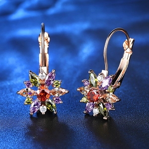 Boucles d'oreilles tournesol en zircon coloré et or rose sur fond texturé sombre